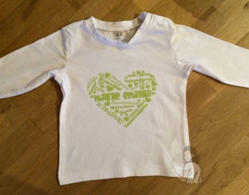 Weißes Langarmshirt mit grünem Herz-Design in verschiedenen Schriftarten.