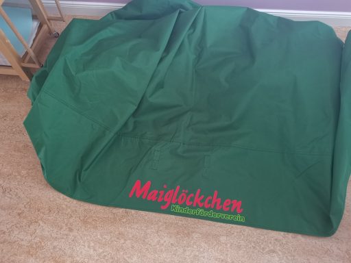 Grüne Abdeckung mit rotem Schriftzug "Maislädchen" am unteren Rand.